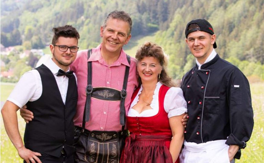 Erlebnishotel Kärnten-Mölltal ***S © Erlebnishotel Kärnten Mölltal Vier Personen lächeln in traditioneller und beruflicher Kleidung im Freien