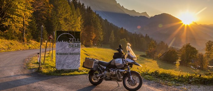 Südkärnten – Karawanken – Slowenien © Alexander Seger Motorrad an Bergstraße bei Sonnenuntergang mit Willkommensschild