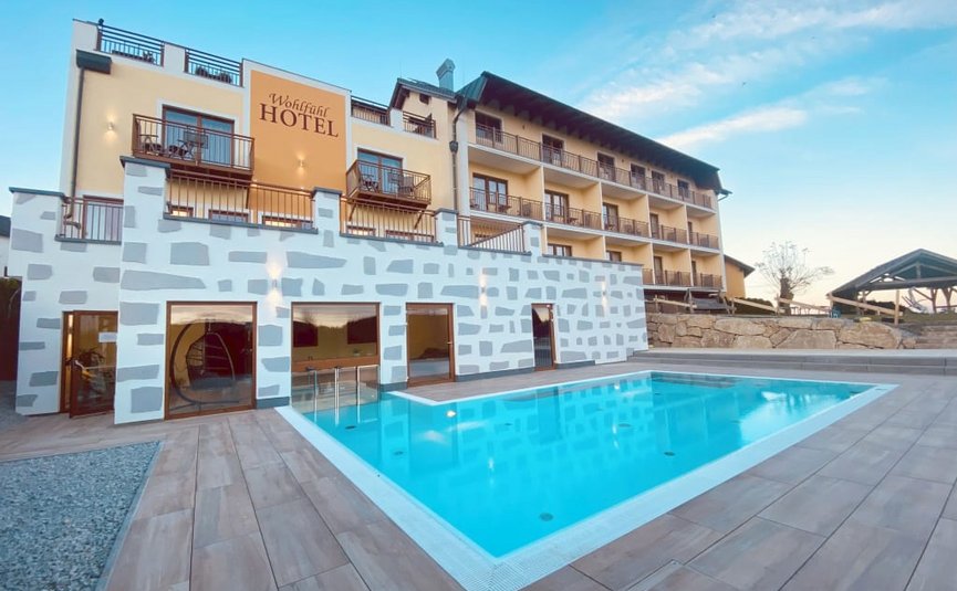 Babymoon im Hotel Rockenschaub Hotel mit Außenpool und Balkonzimmern unter blauem Himmel