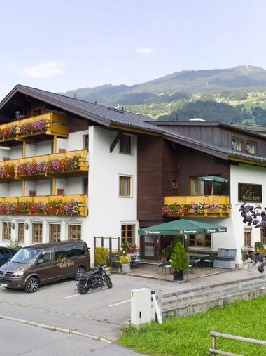 Motorradurlaub © Hotel Both Hotelgebäude mit Balkonblumen und Bergen im Hintergrund