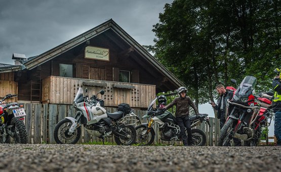 Motorradurlaub im Zillertal – Gerlos Alpenstraße © Moppetfoto.de Motorradfahrer vor einer Holzhütte mit Motorrädern bei bewölktem Himmel