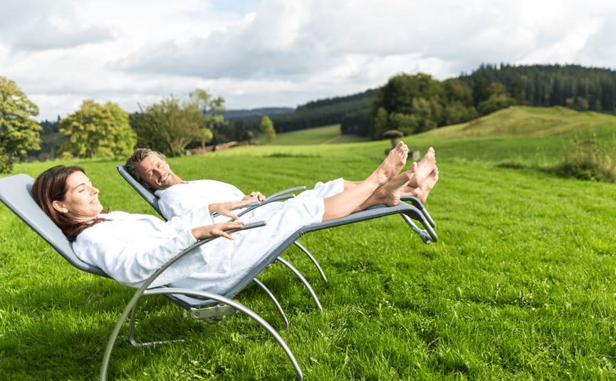 Hot Deal 5= 4 Paar entspannt auf Liegestühlen im grünen Feld bei bewölktem Himmel
