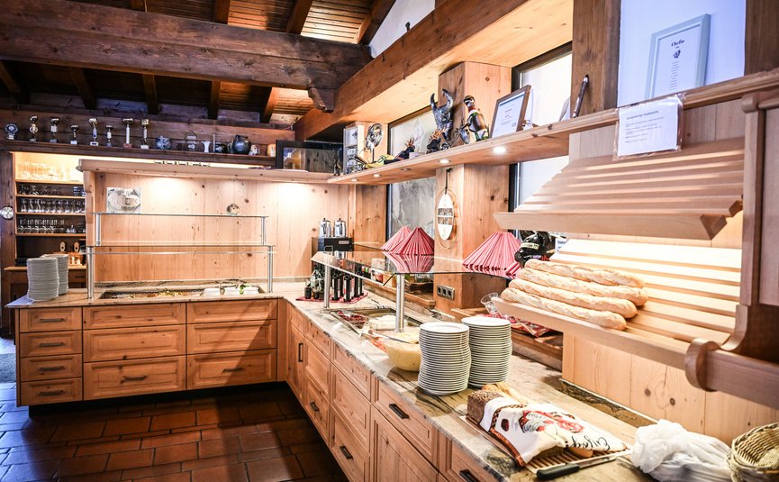 Rustikale Buffet-Theke mit Brot, Tellern und Gläsern in gemütlichem Holzinterieur