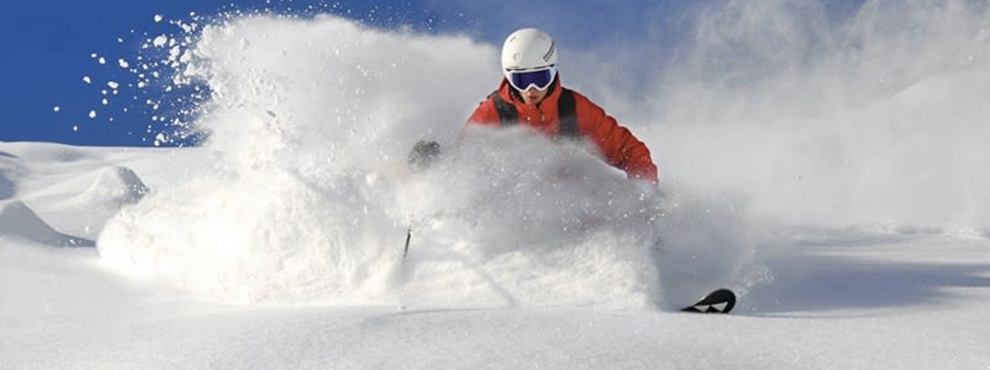 Ski und Spaß im Zillertal 4=3 Skifahrer fährt im Pulverschnee bei blauem Himmel