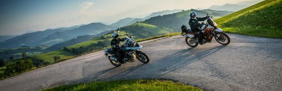 Wald4teler Kurvengaudi Zwei Motorradfahrer auf kurviger Bergstraße mit grünen Hügeln und blauem Himmel