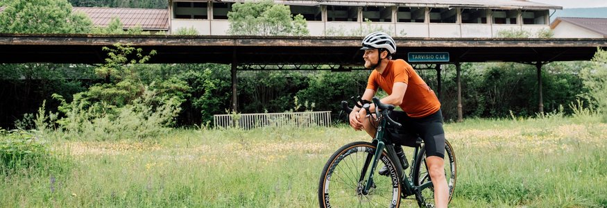 Gravel-Wundertüte Wörthersee © Region Wörthersee Rosental Tourismus GmbH - Chris Perkles Radfahrer in Orange trinkt Pause neben Haus im grünen Gebiet