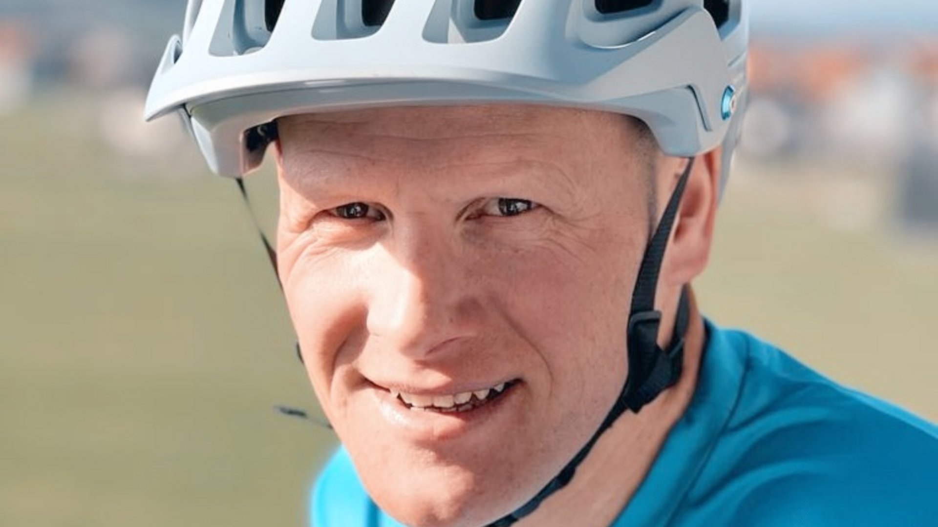 Gravelbikeurlaub im Hotel Rössle
 © Hotel Rössle GmbH Nahaufnahme eines lächelnden Mannes mit weißem Fahrradhelm und blauem Shirt