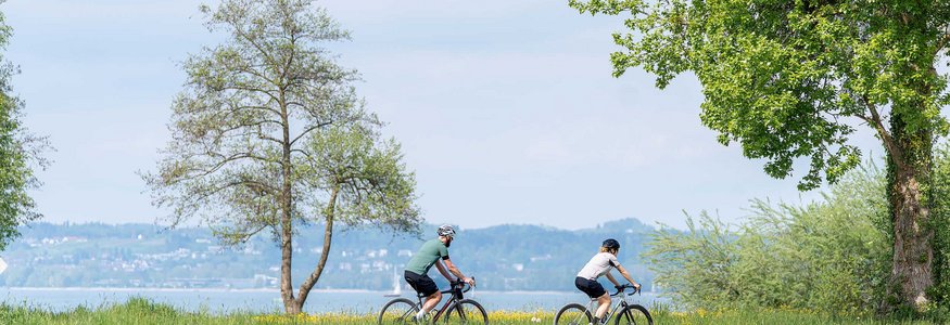 Zwei Radfahrer fahren auf einem Weg am See entlang im Frühling