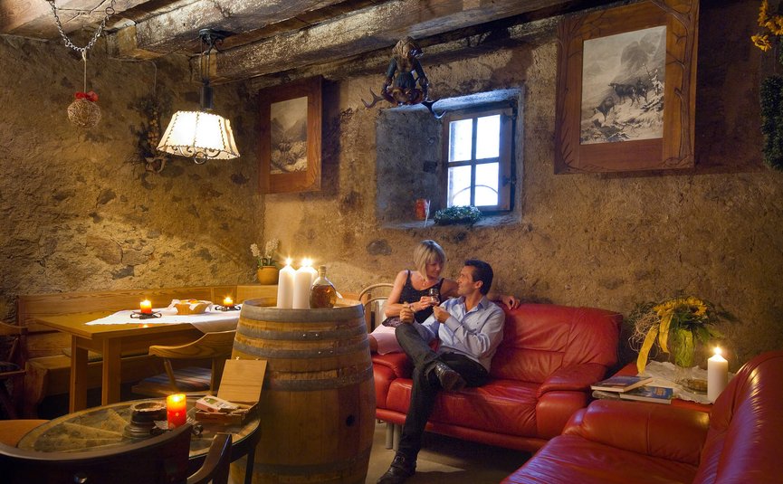 Hotel & Südtiroler Gasthaus Der Gassenwirt *** © Hotel Gassenwirt Paar genießt ein Getränk in rustikalem Wohnzimmer mit Kerzenlicht