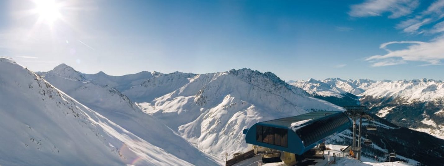 Berggenusswochen Sonniger verschneiter Skiberg mit Skilift und Bergen im Hintergrund
