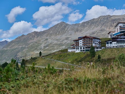 Alpenhotel Laurin © studio22.at - Marcel Hagen Alpenhotel am Hang mit Bergpanorama unter blauem Himmel