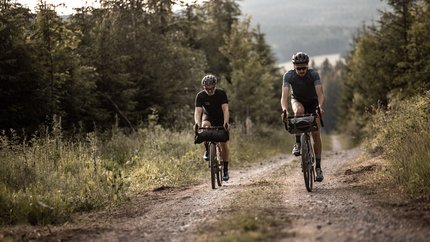 2. Women's Gravelcamp am Sportpark Rabenberg © Martin Matula Zwei Radfahrer fahren auf einem Waldweg bei bewölktem Himmel