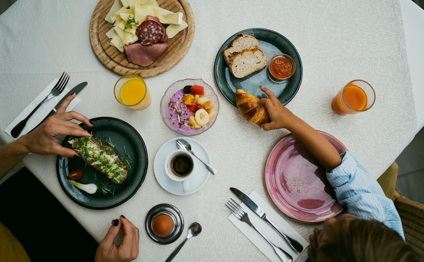 Frühstückstisch mit Aufschnitt, Brot, Croissant, Ei, Kaffee und Orangensaft