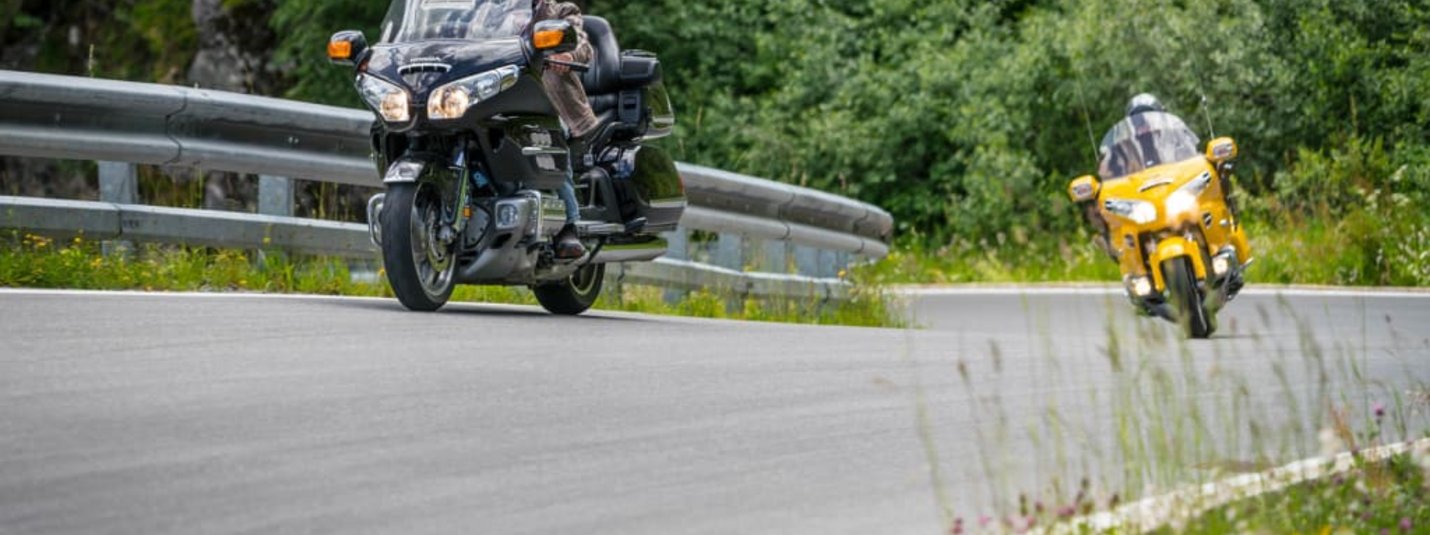 Zwei Motorräder fahren auf einer kurvigen Straße mit Grünflächen