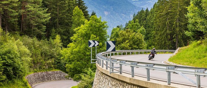 Motorradfahrer fährt auf kurviger Bergstraße im Wald