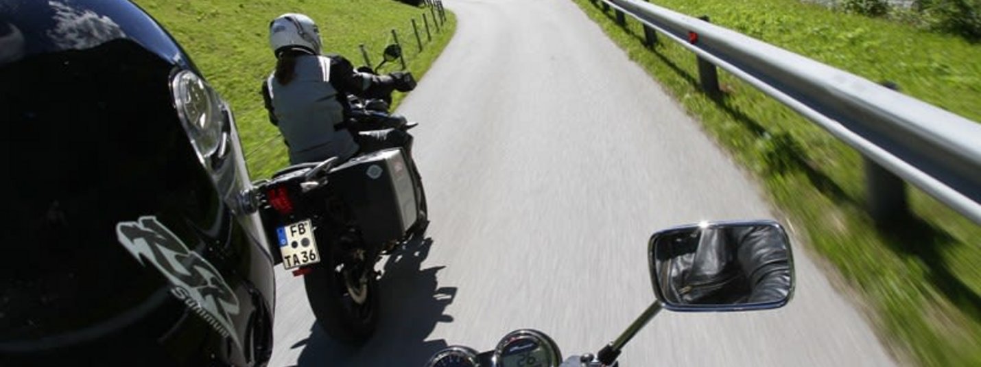 Super Tourenwoche Zwei Motorradfahrer fahren auf einer kurvenreichen Bergstraße durch grüne Landschaft