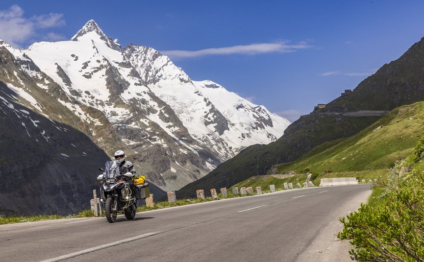Erlebnishotel Kärnten-Mölltal ***S © Alexander Seger Motorradfahrer auf Bergstraße mit schneebedecktem Gipfel im Hintergrund