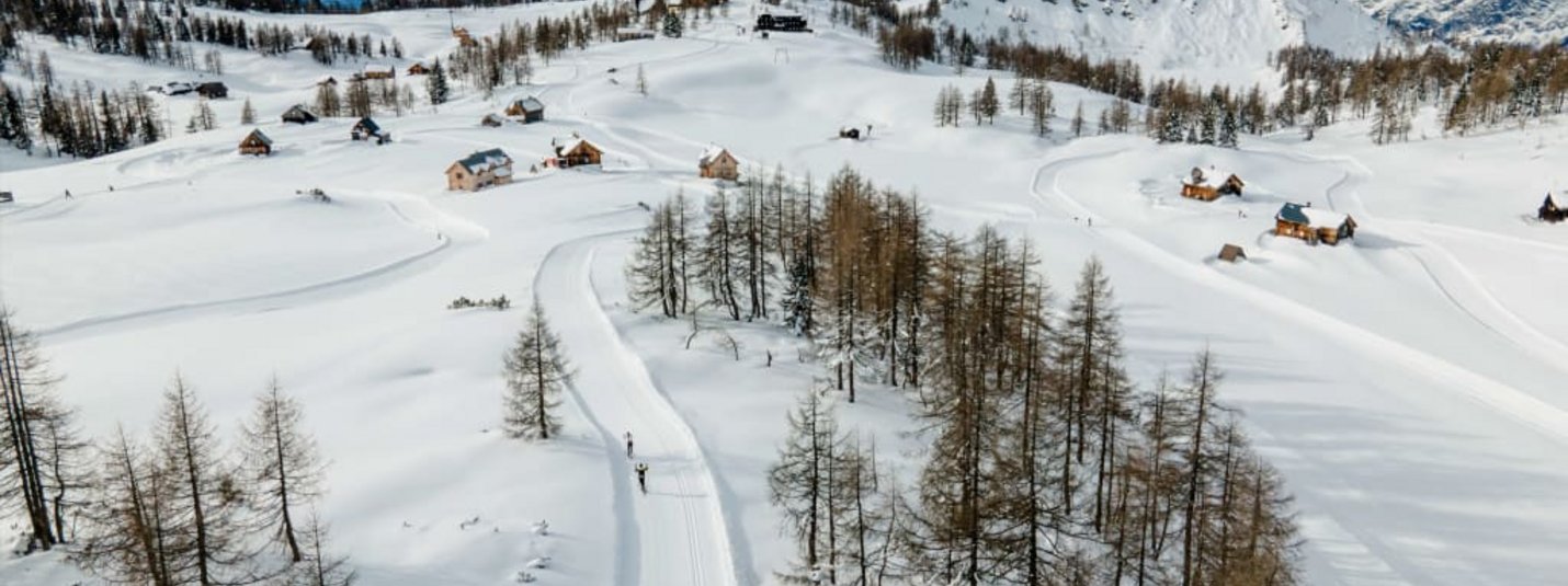Schneebedeckte Berge mit verstreuten Häusern und Nadelbäumen im Winter