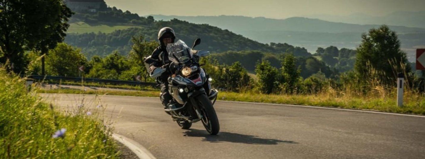Kurven Training Motorradfahrer auf einer kurvigen Landstraße mit Hügeln und Schloss im Hintergrund