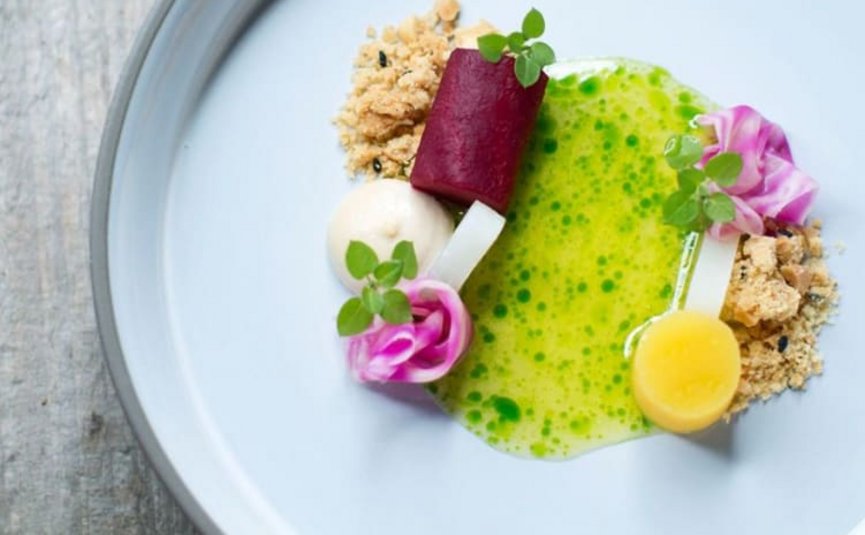 Babymoon im Hotel Rockenschaub Fein angerichtetes Gericht mit Gemüse, Sauce und essbaren Blumen auf weißem Teller