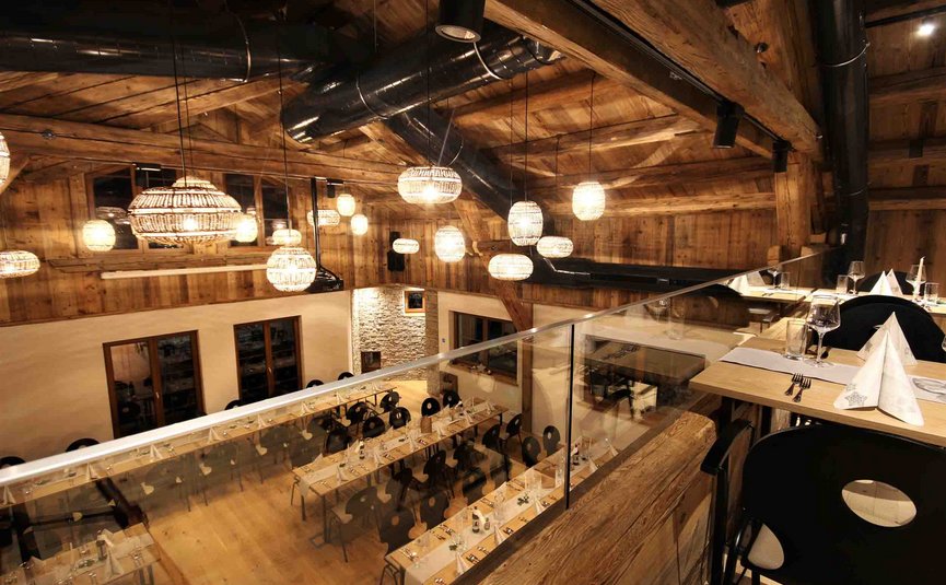 Gemütliches Restaurant mit Holzbalken, warmen Lampen und gedeckten Tischen