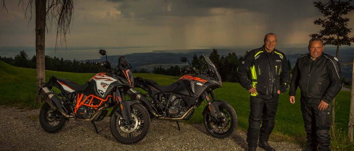 Hotel Bergblick © Moppetfoto.de Zwei Männer in Motorradkleidung neben zwei KTM-Motorrädern vor dunklen Wolken