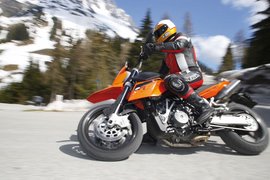 4 Touren Bike Woche Motorradfahrer in Schutzkleidung fährt in den Bergen bei Schnee und Bäumen