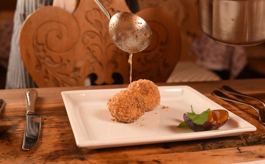 Hotel & Südtiroler Gasthaus Der Gassenwirt *** © Hotel Gassenwirt Kirschknödel mit Butter und Pflaume auf einem weißen Teller