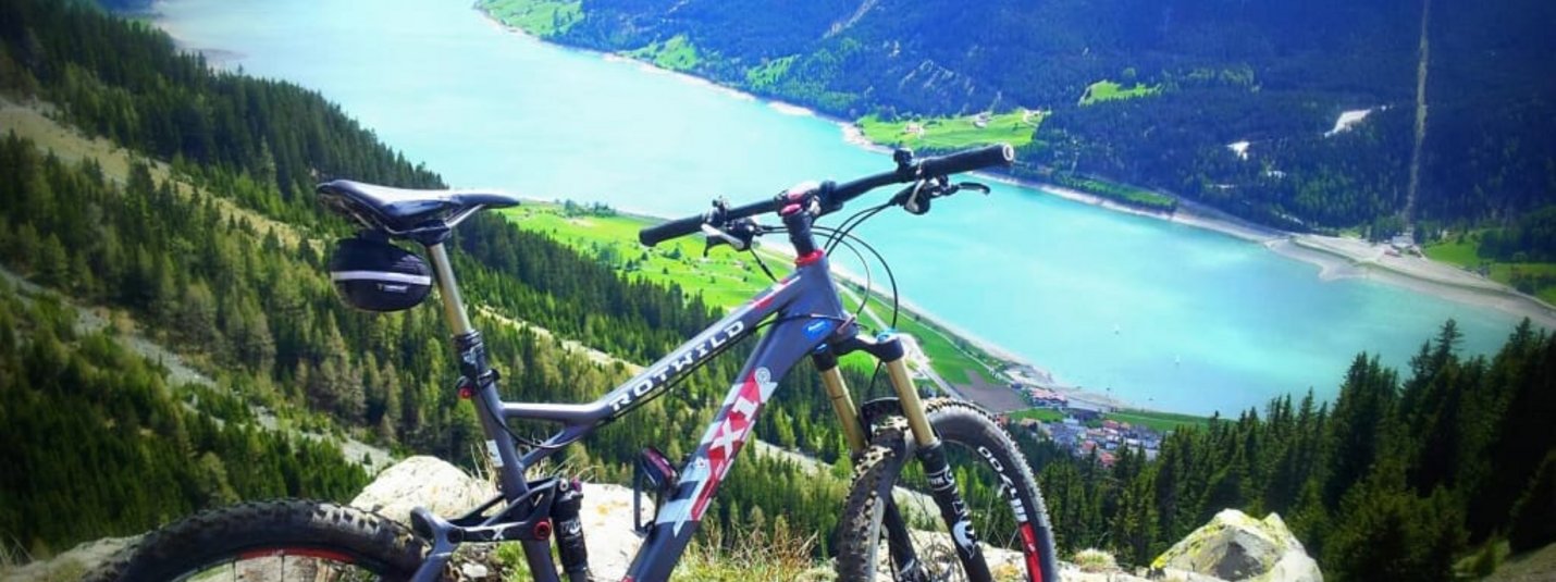 Mountainbike auf Felsen mit Blick auf See und Berge