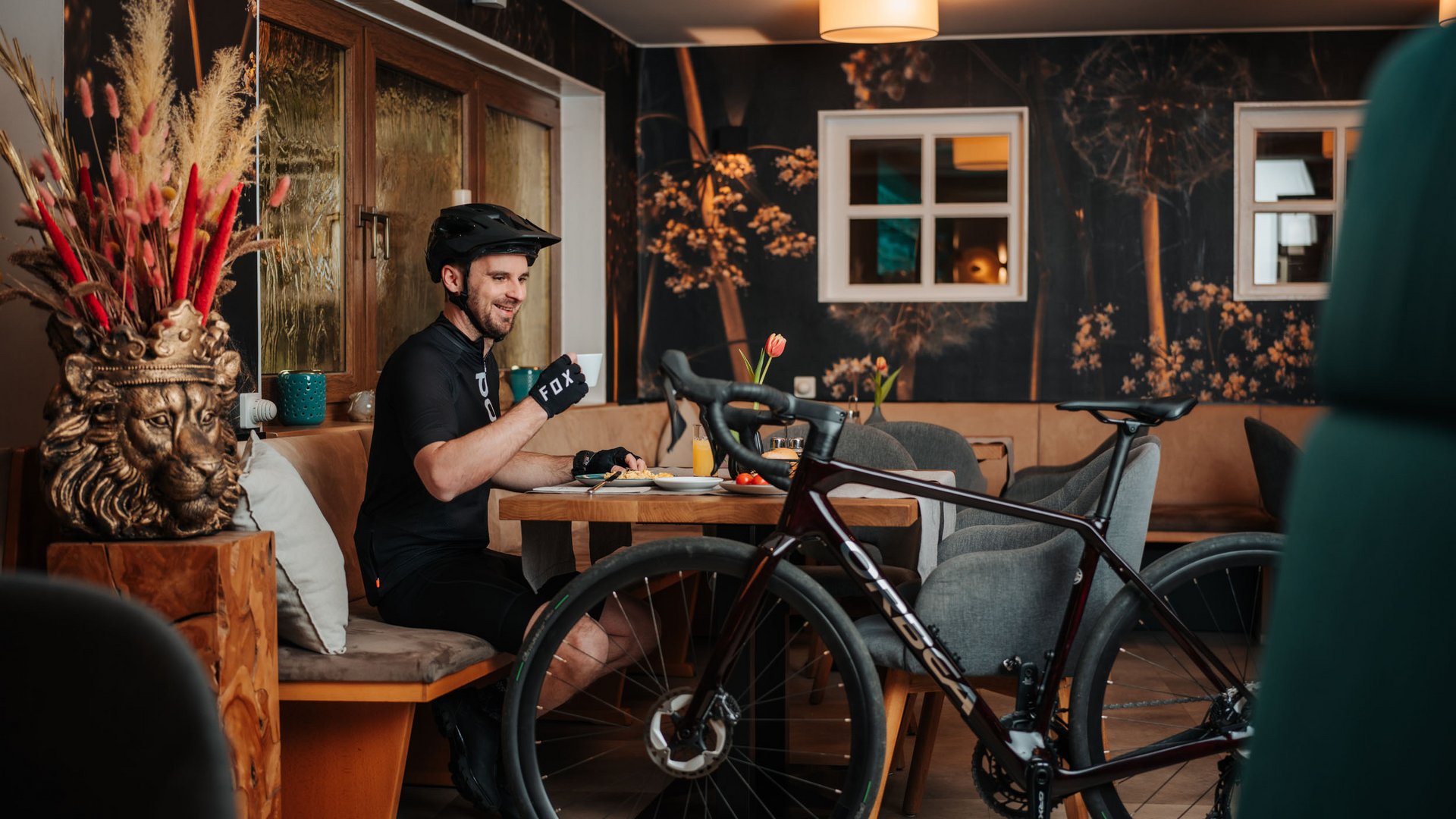 Gravelabenteuer zwischen See & Nockbergen © Martin Hoffmann Radfahrer in schwarzer Ausrüstung trinkt Kaffee neben seinem Fahrrad in Café