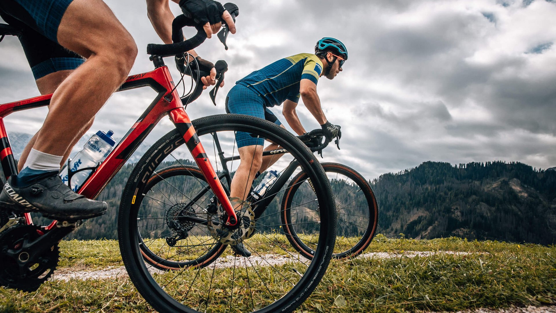 Gravel-Wochenende in San Vigilio © Jens Scheibe Zwei Radfahrer fahren auf einem Bergpfad bei bewölktem Himmel