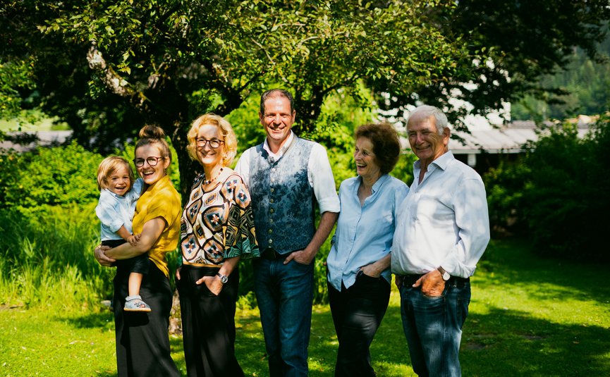 Drei Generationen lächelnder Familie im Garten an einem sonnigen Tag