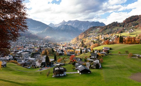 Motorradurlaub im Montafon – Silvretta © Montafon Tourismus GmbH - Stefan Kothner Bergdorf mit Häusern und grünen Wiesen im Herbst vor bewölkten Alpen