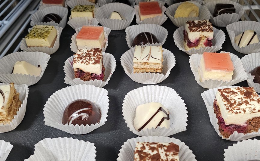 Verschiedene kleine Pralinen und Kuchenstücke in Papierförmchen auf Tablett