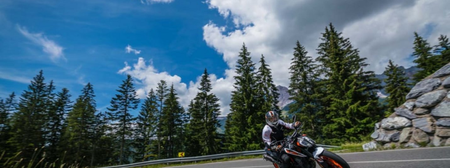 2 Tage Motorradurlaub Motorradfahrer fährt auf kurviger Bergstraße bei sonnigem Wetter