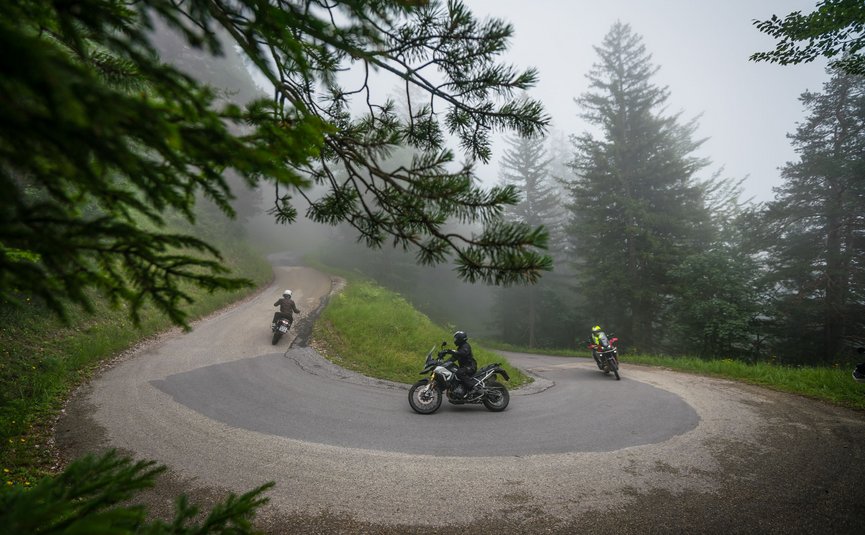 Motorradfahrer auf serpentinenreicher bergstraße bei nebeligem wetter