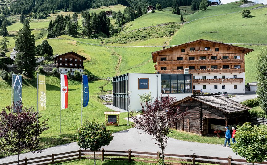 DAS UNTERRAIN lifestyle hotel **** © Armin Kleinlercher Alpenlandschaft mit Hotel, moderner und traditioneller Architektur und grünen Hügeln