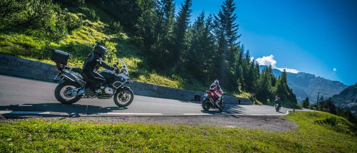 Motorradfahrer auf kurviger Bergstraße bei sonnigem Wetter