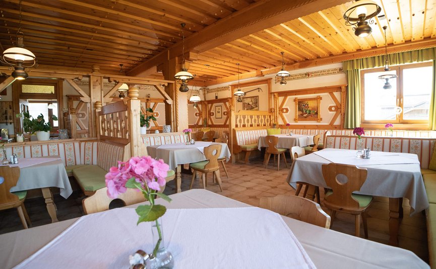Gemütliches, traditionell eingerichtetes Restaurant mit Holzmöbeln und Blumen auf den Tischen