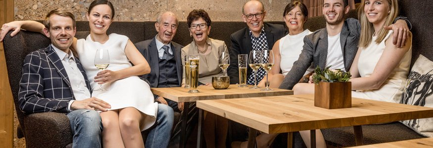 Familie sitzt zusammen in gemütlichem Raum mit Getränken auf dem Tisch