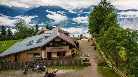 Qualitätsversprechen © Moppetfoto.de Berghütte mit Motorrädern und Nebel über dem Tal bei bewölktem Himmel