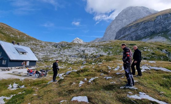 Motorradurlaub in der Ferienregion Wolfsberg – Region Lavanttal © Viktor Sator Drei Männer in Motorradkleidung wandern in bergiger Landschaft bei Hütte