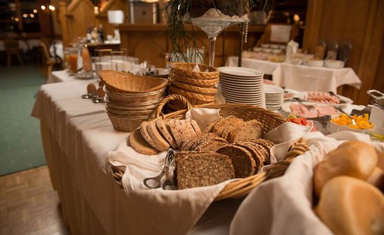 Buffet mit verschiedenen Brotsorten und Brötchen in Körben auf weißer Tischdecke