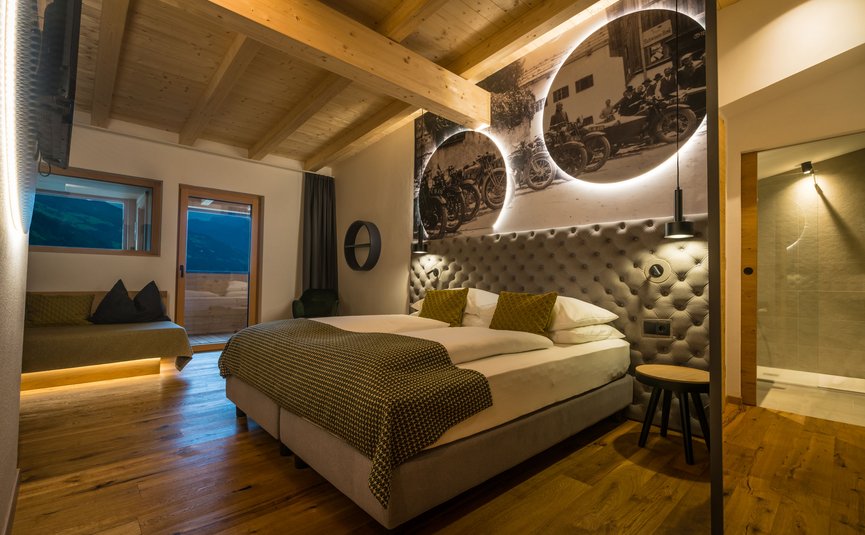 Gemütliches Hotelzimmer mit Holzboden und beleuchtetem Vintage-Motorradbild