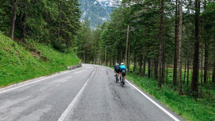 Austria Giro unsupported © Hotel Melodia del Bosco Zwei Radfahrer auf bergiger Straße durch einen Wald mit Bergen im Hintergrund