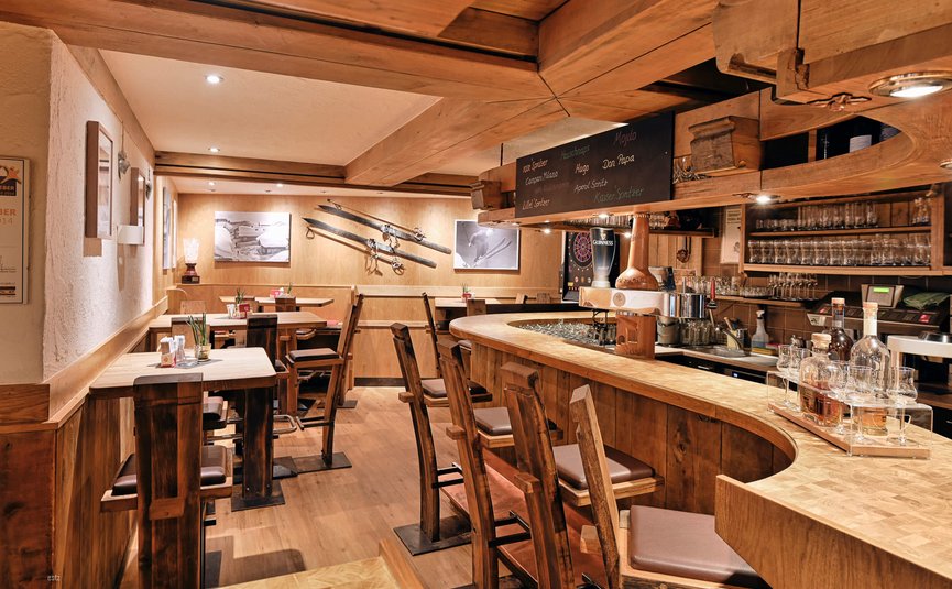 Gemütliche Holzbar mit hohen Stühlen und Skidekoration an der Wand