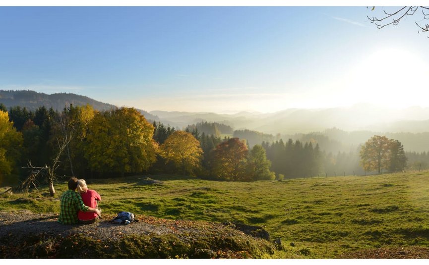Goldener Herbst auf der Mühl4tler Alm Paar sitzt auf Felsen und genießt sonnige Herbstlandschaft mit Bergen