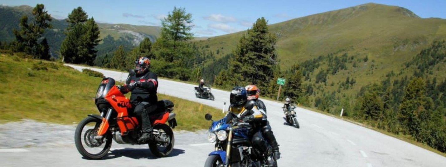 Genuss Tage für Motorradfahrer Motorradfahrer fahren auf kurviger Bergstraße bei sonnigem Wetter