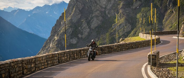 Ötztal – Timmelsjoch © Moppetfoto.de Motorradfahrer auf kurvenreicher Bergstraße mit Steinmauer und Bergen im Hintergrund