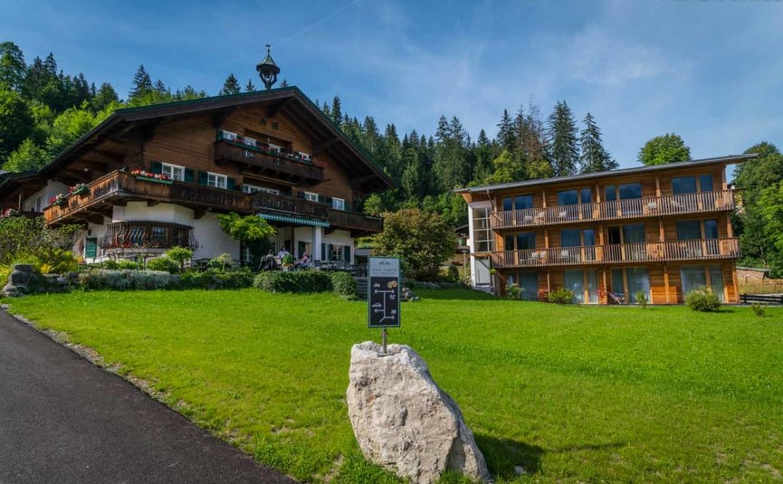 Traditionelles Holzhaus neben modernem Holzhaus in grüner Landschaft